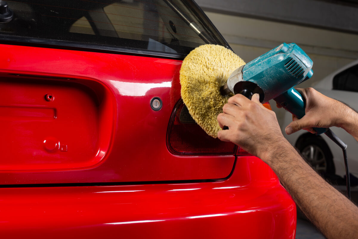 Polishing red car hatch at Grandcity autobody shop in Vancouver